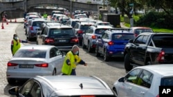 FILE - Traffic marshals direct vehicles at a drive-thru COVID-19 testing clinic at Bondi Beach in Sydney, Australia, on Jan. 8, 2022.