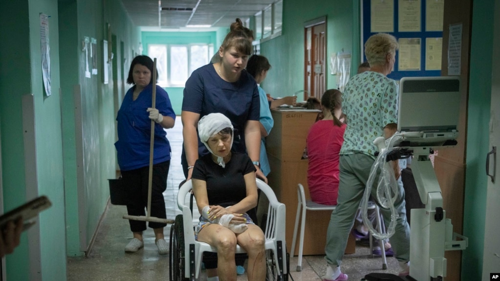 医院护士用轮椅推着一名在俄罗斯导弹袭击克列门丘格市一处购物中心时受伤的女子。(2022年6月28日)(photo:VOA)
