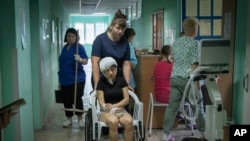 医院护士用轮椅推着一名在俄罗斯导弹袭击克列门丘格市一处购物中心时受伤的女子。(2022年6月28日)
