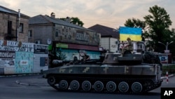 Ukrainian soldiers ride atop a tank through a street in Pokrovsk, Donetsk region, eastern Ukraine, July 8, 2022.