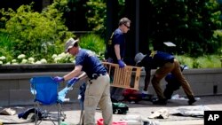 Agentes del FBI recolectan evidencia mientras retiran pertenencias abandonadas un día después de un tiroteo en Highland Park, Illinois, el martes 5 de julio de 2022. (AP Foto/Charles Rex Arbogast)