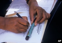 Seorang perawat menulis pada botol sampel darah yang diambil dari seorang peserta studi sifilis tahun 1950-an di Tuskegee, Alabama. (Arsip Nasional via AP)