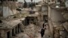 在被空袭严重破坏的叙利亚伊德利卜省，妇女们行走在一片废墟中。（2020年3月12日）