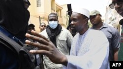 L'opposant sénégalais Ousmane Sonko discute avec des membres de la police devant sa résidence à Dakar le 17 juin 2022.