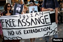 Pendukung Julian Assange memegang spanduk saat protes menentang ekstradisi pendiri WikiLeaks itu dari Inggris ke AS, di Athena, Yunani, 20 Juni 2022. (Foto: Reuters)