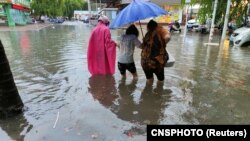 Pedestrians wade through floodwaters amid heavy rainfall as Typhoon Chaba hits Sanya in Hainan province, China, on July 2, 2022. Forecasters said the typhoon weakened into a tropical storm on Monday, but heavy rain is expected in central and eastern China in coming days
