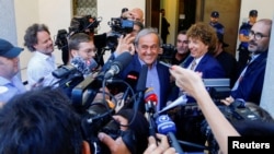 Mantan Presiden UEFA Michel Platini memberi isyarat di depan anggota media setelah persidangan di Pengadilan Kriminal Federal Swiss di Bellinzona, Swiss 8 Juli 2022. (REUTERS/Arnd Wiegmann)