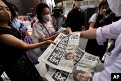 An employee distributes extra editions of the Yomiuri Shimbun newspaper reporting that Japan's former Prime Minister Shinzo Abe was shot, in Tokyo, July 8, 2022.