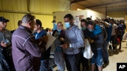 Inmigrantes hacen fila para tomar un autobús comercial al aeropuerto de San Antonio en Eagle Pass, Texas, el 23 de mayo de 2022. (AP Photo/Dario Lopez- Molinos)