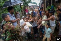 A Bangladeshi army soldier distributes relief material to flood-affected people in Sylhet, Bangladesh, Wednesday, June 22, 2022. (AP Photo/Mahmud Hossain Opu)