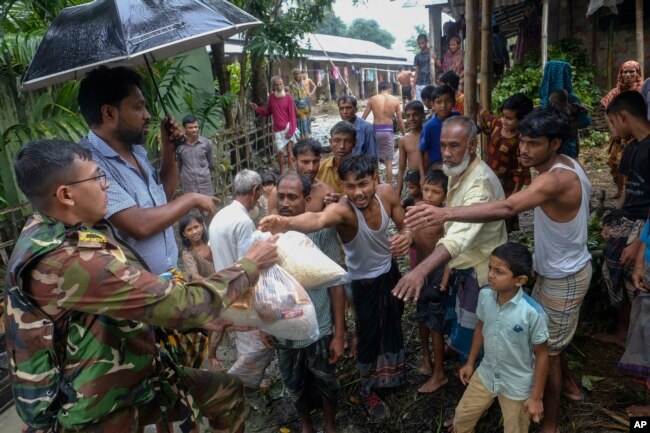 A Bangladeshi army soldier distributes relief material to flood-affected people in Sylhet, Bangladesh, Wednesday, June 22, 2022. (AP Photo/Mahmud Hossain Opu)