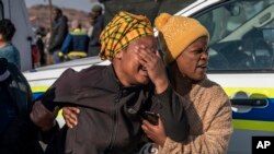 A woman weeps at the scene of an overnight bar shooting in Soweto, South Africa, Sunday July 10, 2022. 