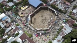 Espectadores se aglomeran cerca de donde se derrumbaron varios palcos armados en forma improvisada y con gente en ellos durante una corrida de toros en la ciudad de El Espinal, departamento de Tolima, en Colombia, el domingo 26 de junio de 2022. (AP Video)