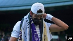 FILE - Italy's Matteo Berrettini wears a mask during his men's singles quarterfinal match at the Wimbledon Tennis Championships in London, July 7, 2021. At Wimbledon, where neither shots nor testing was required, three of the men's top 20 seeds withdrew over the first four days of action because they got COVID-19.