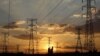 FILE - Locals walk past electricity pylons during frequent power outages from South African utility Eskom, in Soweto, South Africa, April 4, 2022.