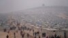 FILE - Syrians walk in a refugee camp for displaced people run by the Turkish Red Crescent in Sarmada district, north of Idlib city, Syria, Nov. 26, 2021.