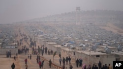 FILE - Syrians walk in a refugee camp for displaced people run by the Turkish Red Crescent in Sarmada district, north of Idlib city, Syria, Nov. 26, 2021.