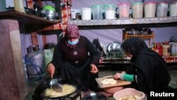 Syrian refugee prepares food with another woman at an informal camp in Deir Zenoun, in the Bekaa valley, Lebanon April 19, 2022. 