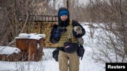 FILE - Ukrainian photographer Maks Levin carries a cat near the line of separation from Russian-backed separatists in Donetsk region, Ukraine, Jan 25, 2022.