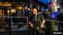 Security forces stand at the site where several people were injured during a shooting outside the London pub in central Oslo, Norway, June 25, 2022.