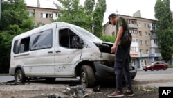 A man inspects a car damaged during shelling in Donetsk, in territory under the government of the Donetsk People's Republic, eastern Ukraine, June 22, 2022.