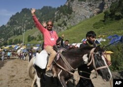 Seorang umat Hindu mengangkat tangannya saat ia memulai ziarah tahunan Amarnath Yatra ke sebuah gua es Himalaya, di Chandanwari, Pahalgam, selatan Srinagar, Kashmir yang dikuasai India, Kamis, 30 Juni 2022. (Foto AP)