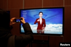 Seorang jurnalis mendokumentasikan layar yang menampilkan sistem bahasa isyarat digital yang digerakkan oleh sistem kecerdasan buatan (AI) Wu Dao 2.0, selama tur ke Akademi Kecerdasan Buatan Beijing (BAAI) di Beijing, China 10 Februari 2022 (foto: ilustrasi).