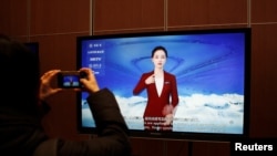 FILE - A journalist documents a screen displaying a digital sign language system driven by the Wu Dao 2.0 artificial intelligence system, during an organized media tour of the Beijing Academy of Artificial Intelligence in Beijing, Feb. 10, 2022.