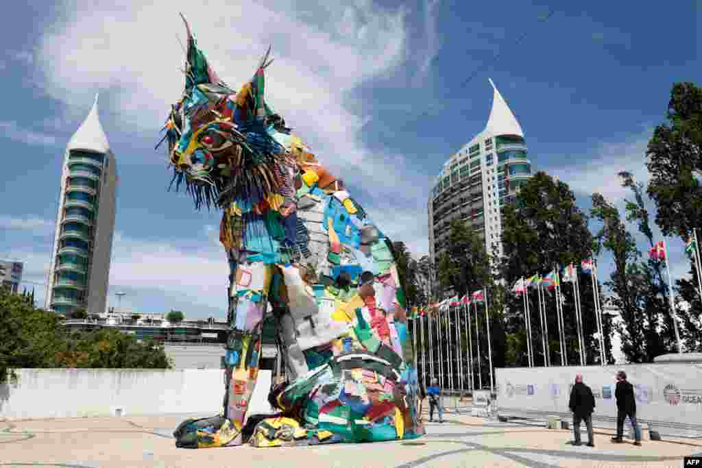 Pejalan kaki berjalan melewati patung yang dibuat dari barang-barang yang didaur ulang karya seniman Portugis Artur Bordalo alias Bordalo II sebagai bagian dari Konferensi Kelautan PBB, di Lisabon, Portugal. (Foto: AFP)&nbsp;