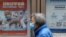 FILE - A person walks past a poster encouraging elderly people to get vaccinated against COVID-19, near a residential compound in Beijing, China, March 30, 2022. 