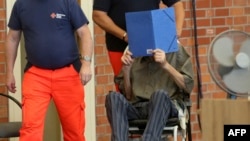 Former Nazi concentration camp guard Josef Schuetz covers his face as he arrives on June 28, 2022, at a gym used as a courtroom in Brandenburg an der Havel, Germany. At 101, Schuetz is the oldest person to go on trial for complicity in war crimes during the Holocaust. 