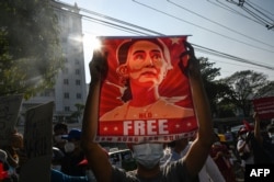 FILE - In this file photo taken on February 15, 2021, a protester holds up a poster featuring Aung San Suu Kyi during a demonstration against the military coup in front of the Central Bank of Myanmar in Yangon.