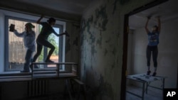 Women work to reconstruct a damaged fire department from Russian strikes, in Makariv, Kyiv region, Ukraine, Wednesday, June 29, 2022. (AP Photo/Nariman El-Mofty)
