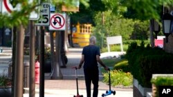 Un hombre recoge los scooters de dos niños un día después de un tiroteo masivo en el centro de Highland Park, Illinois, el martes 5 de julio de 2022. (Foto AP/Charles Rex Arbogast)