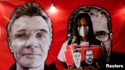 A demonstrator holds a sign with images of British journalist Dom Phillips and indigenous expert Bruno Pereira, during a protest against Brazilian President Jair Bolsonaro's government in Brasilia, Brazil June 15, 2022. 