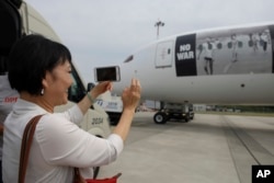 Phan Thị Kim Phuc, the girl shown in a now famous photo of a 1972 Vietnam napalm attack, takes a picture of a plane transporting refugees fleeing the war in Ukraine to Canada, from Frederic Chopin Airport in Warsaw, Poland, July 4, 2022.