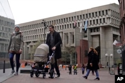 FILE - Pedestrians walk near three flag poles flying the American flag, the Commonwealth of Massachusetts flag, and the City of Boston flag, from left, outside Boston City Hall, Monday, May 2, 2022, in Boston. Supreme Court has ruled that Boston violated the free speech rights of a conservative activist when it refused his request to fly a Christian flag on a flagpole outside City Hall. (AP Photo/Charles Krupa)