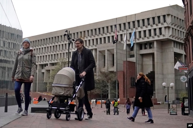 FILE - Pedestrians walk near three flag poles flying the American flag, the Commonwealth of Massachusetts flag, and the City of Boston flag, from left, outside Boston City Hall, Monday, May 2, 2022, in Boston. Supreme Court has ruled that Boston violated the free speech rights of a conservative activist when it refused his request to fly a Christian flag on a flagpole outside City Hall. (AP Photo/Charles Krupa)