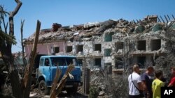 FILE: Local residents stand next to damaged residential building in the town of Serhiivka, located about 50 kilometers southwest of Odesa, Ukraine. Taken 7.1.2022