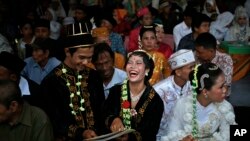 Seorang pasangan pengantin tampak tertawa ketika menerima buku nikah milik mereka dalam acara pernikahan massal di Jakarta, pada 31 Desember 2017. (Foto: AP/Dita Alangkara)