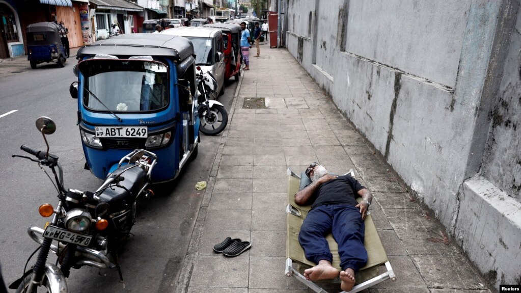 FILE PHOTO: A man sleeps on a folding bed on a pavement as he waits in queue to buy petrol due to fuel shortage, amid the country's economic crisis, in Colombo, Sri Lanka, June 17, 2022. 