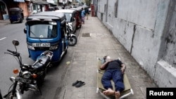 FILE PHOTO: A man sleeps on a folding bed on a pavement as he waits in queue to buy petrol due to fuel shortage, amid the country's economic crisis, in Colombo, Sri Lanka, June 17, 2022. 