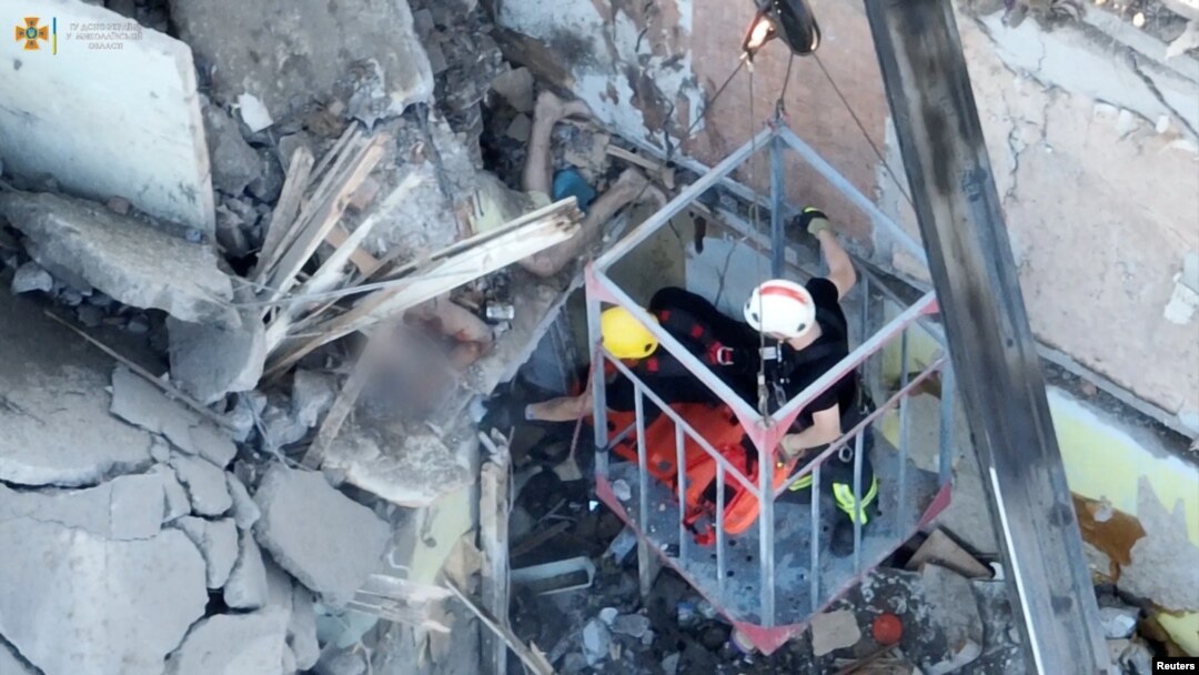 Rescue workers try to evacuate an injured man from a residential building hit by a Russian military strike, in Mykolaiv, Ukraine, June 29, 2022, in this screen grab obtained from a handout video. (State Emergency Service of Ukraine/Reuters)