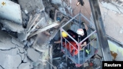 Rescue workers try to evacuate an injured man from a residential building hit by a Russian military strike, in Mykolaiv, Ukraine, June 29, 2022, in this screen grab obtained from a handout video. (State Emergency Service of Ukraine/Reuters)