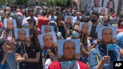 Sejumlah demonstran yang marah membawa foto aktivis Nizar Banat, dan meneriakkan slogan antipemerintah dalam aksi protes di Tepi Barat, Ramallah, pada 24 Juni 2021. (Foto: AP/Nasser Nasser)