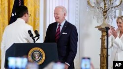 President Joe Biden shakes hands with youth activist Javier Gomez after being introduced by Gomez during an event to celebrate Pride Month in the East Room of the White House, Wednesday, June 15, 2022, in Washington. First lady Jill Biden applauds at right.