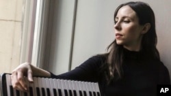 Erica Mancini, an accordionist, poses before taking the stage, June 17, 2022, at Bohemian National Hall in New York. Mancini has suffered three COVID-19 infections, the most recent this past May. Medical experts warn that we'll be seeing more multiple reinfections given how long the pandemic is stretching on.