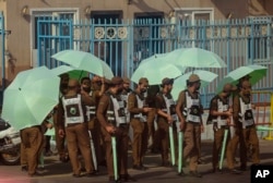 Saudi traffic policemen raise umbrellas at the Mina tent camp, in the Saudi Arabia's holy city of Mecca, Tuesday, July 5, 2022. Saudi Arabia is expected to receive one million Muslims to attend Hajj pilgrimage, which will begin on July 7, after two years of limiting the numbers because coronavirus pandemic. (AP Photo/Amr Nabil)