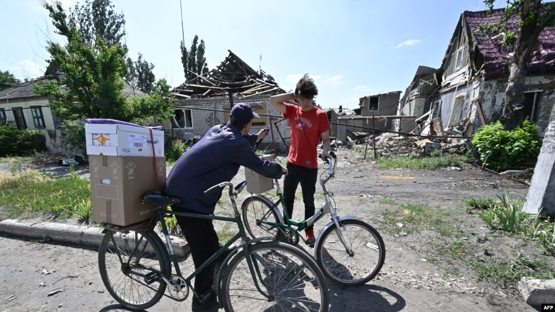 Local residents carry boxes with a humanitarian aid in the town of Siversk, Donetsk Oblast, on July 3, 2022, amid Russian invasion of Ukraine.