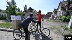 Local residents carry boxes with a humanitarian aid in the town of Siversk, Donetsk Oblast, on July 3, 2022, amid Russian invasion of Ukraine.